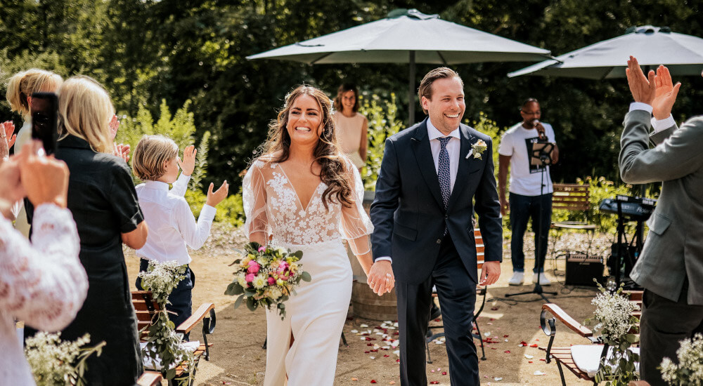 Foto kusecphotography 2022, Weingut Wasem Ingelheim Auszug lachendes Brautpaar nach Trauung mit Traurednerin Verena